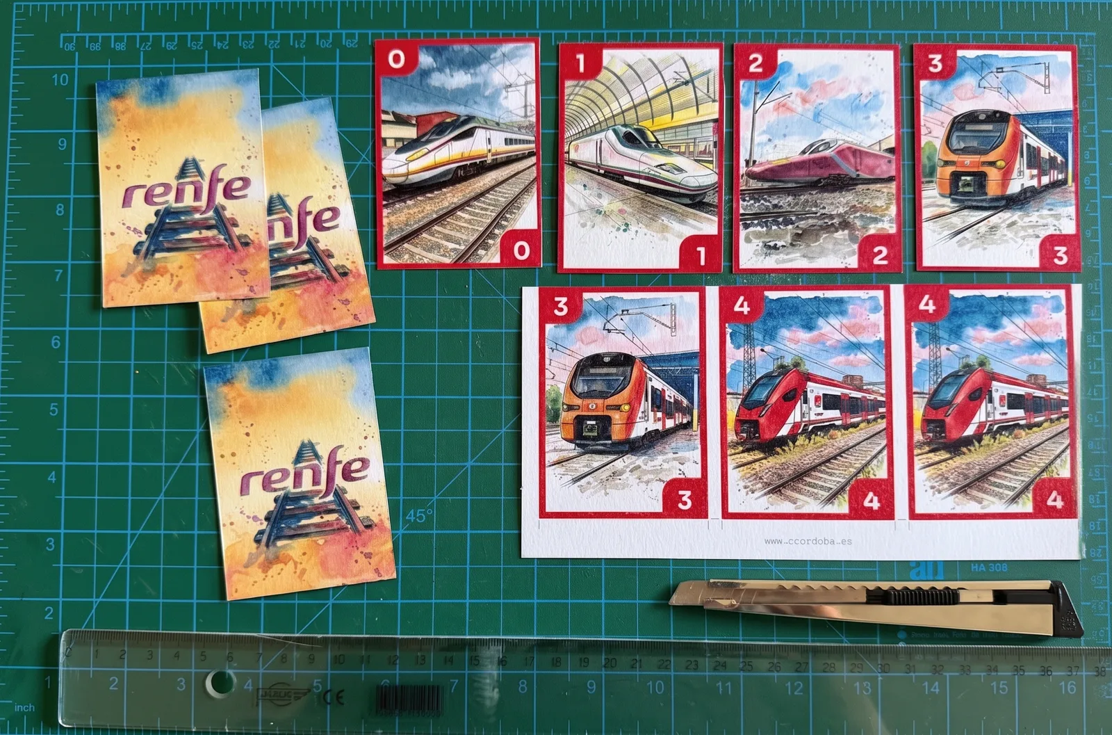 Cartas del mazo de trenes recién impresas, siendo recortadas a mano con cúter y regla sobre una base de corte